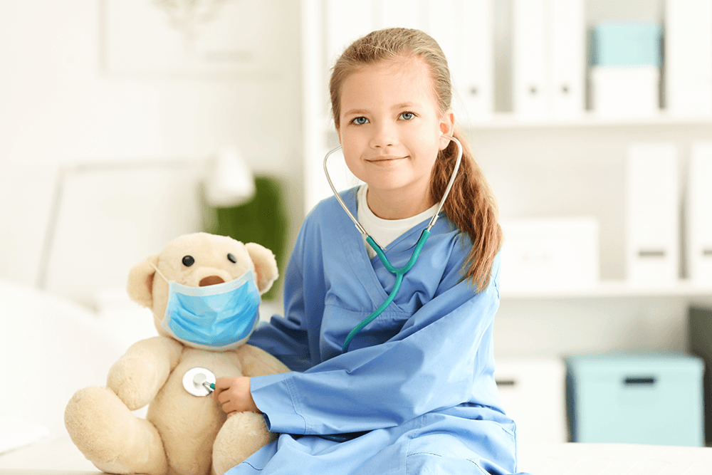 Little girl dressed as doctor checking heart of teddy bear with stethoscope
